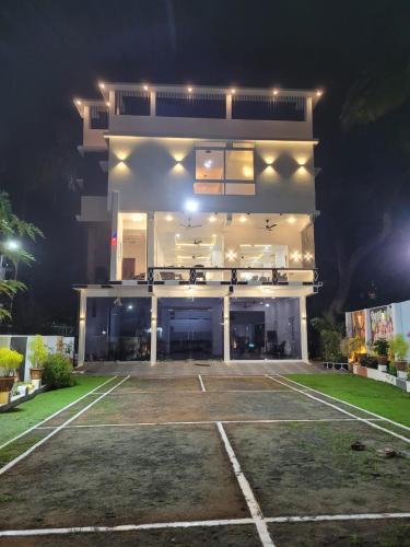 a large white building with a parking lot at night at Yogis Inn in Kozhikode