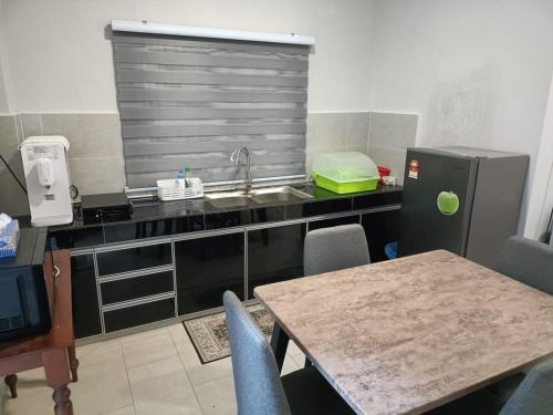 a kitchen with a sink and a table with chairs at RINA HOMESTAY Kemaman in Cukai