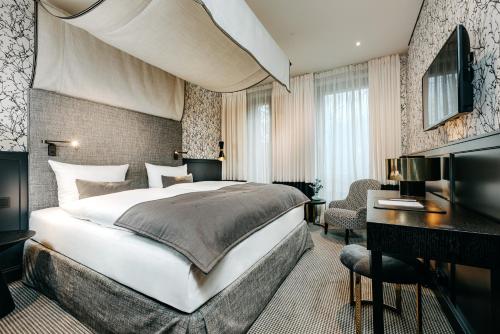 アンダーナッハにあるHotel am Ochsentorの大きなベッドとデスクが備わるホテルルームです。
