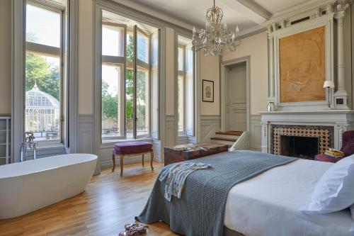 1 dormitorio con bañera, cama y chimenea en Château Les Carrasses, en Capestang