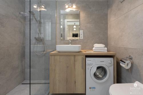 a bathroom with a sink and a washing machine at Shellter Apartments 117 M - by Jantar Apartamenty in Rogowo