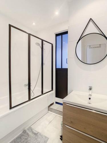 une salle de bain avec un lavabo et un miroir au mur dans l'établissement L'horloge II - 2 pièces - 15 min Palais - Cannes, à Cannes
