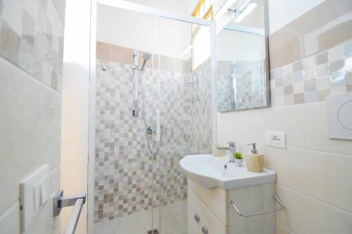 La salle de bains est pourvue d'un lavabo et d'une douche avec un miroir. dans l'établissement Home Paola, à Noto