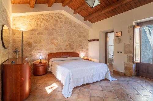 a bedroom with a bed and a stone wall at Il Flauto Magico in Modica