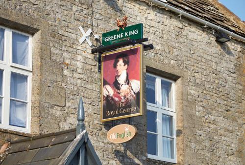 a sign on the side of a brick building at Royal George Hotel by Greene King Inns in Birdlip