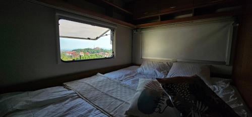 a bed in a small room with a window at Campervan romantic getaway in Old Town Brasov in Braşov