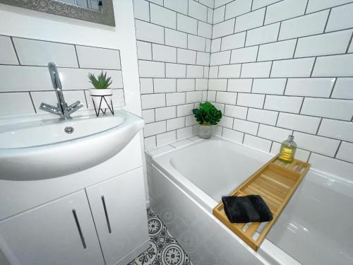y baño blanco con lavabo y bañera. en Modern House with Fast WIFI & FREE Parking - Recently Refurbished - Contractor Friendly by IRWELL STAYS, en Cronton