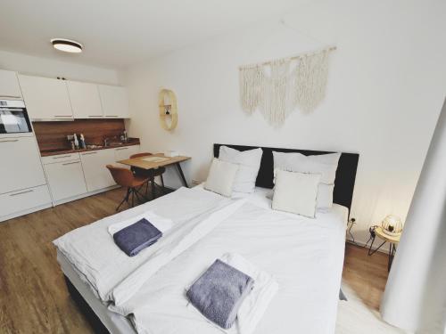 a large white bed in a room with a kitchen at TiCasa BOHO - Zentral-Outlet-Balkon-Parkplatz-SmartTV-Unique in Metzingen