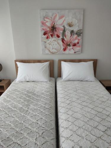 dwa łóżka z białymi poduszkami i obrazem na ścianie w obiekcie AniBo studios and apartments ZERO POINT 35 w Salonikach