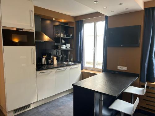 a kitchen with white cabinets and a black counter top at Appartement Censier Daubenton in Paris