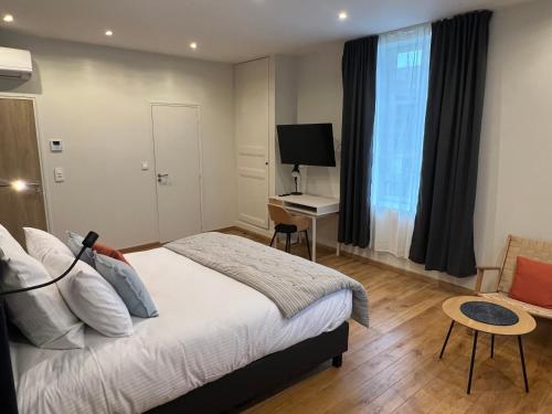 une chambre avec un lit et un bureau avec une télévision dans l'établissement La Grande-Ourse, à Charleville-Mézières