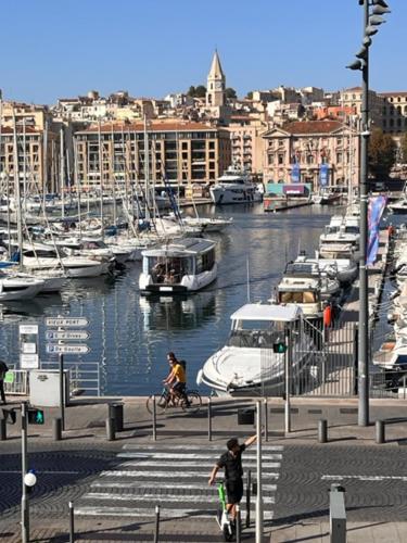 um homem a andar de bicicleta ao lado de uma marina com barcos em T4 Marseille Vue imprenable sur Vieux Port em Marselha