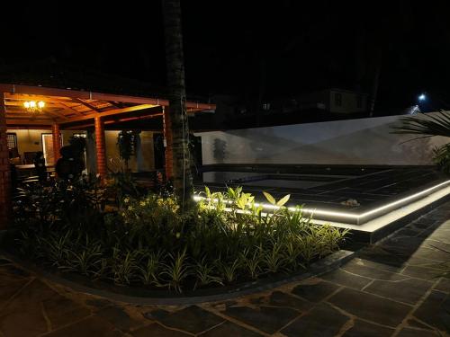 un jardín con plantas frente a un edificio por la noche en Ooru, en Udupi