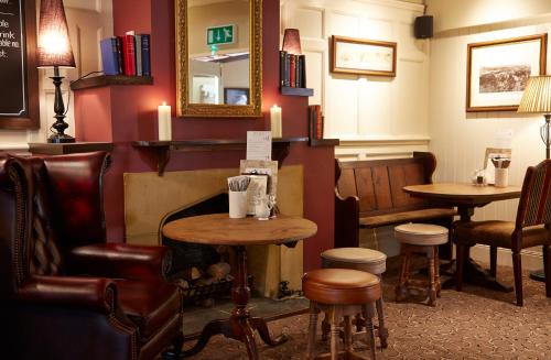 a bar with two tables and chairs and a mirror at Royal George Hotel by Greene King Inns in Birdlip
