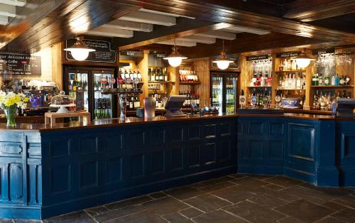 um bar com armários azuis e garrafas de álcool em Royal George Hotel by Greene King Inns em Birdlip