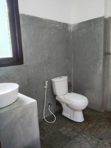 a bathroom with a white toilet and a sink at Arazo villa in Unawatuna