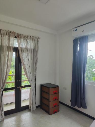 a room with two windows with curtains and a dresser at Arazo villa in Unawatuna
