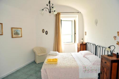 Un dormitorio con una cama y una ventana y una silla. en Villa Maria Antonietta, en Vietri