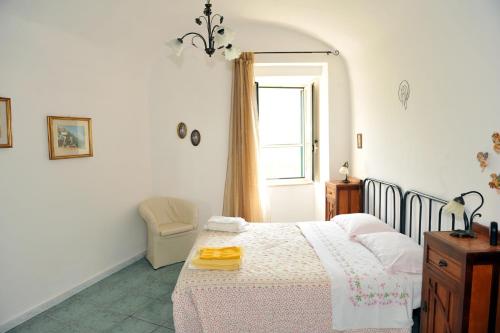 1 dormitorio con cama, ventana y silla en Villa Maria Antonietta, en Vietri