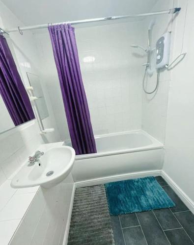 een witte badkamer met een wastafel, een bad en een douche bij Cozy 2 Bed Flat in Cricklewood in Londen