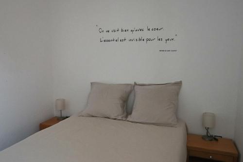 - une chambre dotée d'un lit avec une citation sur le mur dans l'établissement Appartement Les Trois Renards-Tassin, à Tassin-la-Demi-Lune