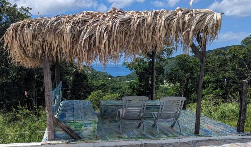 a table and chairs under a straw roof at Savane Paille in Deshaies