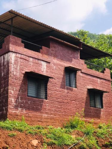a red brick building with three windows on it at Rohan Homestay By Traviget Hospitality, Dapoli-Konkan in Harnai