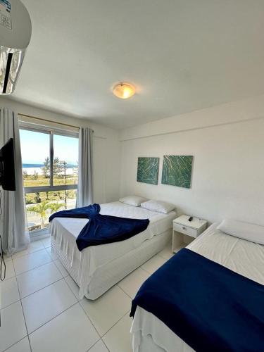 a bedroom with two beds and a large window at MANDAI APART in Cabo Frio
