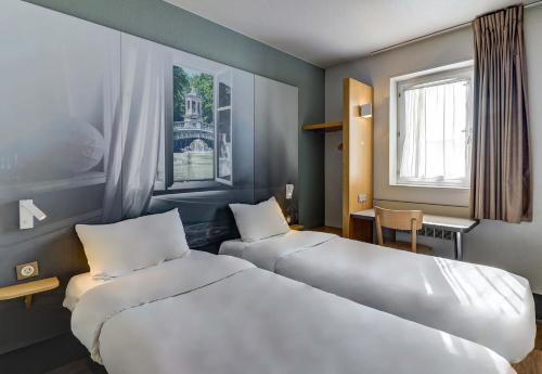 a hotel room with two beds and a window at B&B HOTEL Dijon Nord Zénith in Dijon