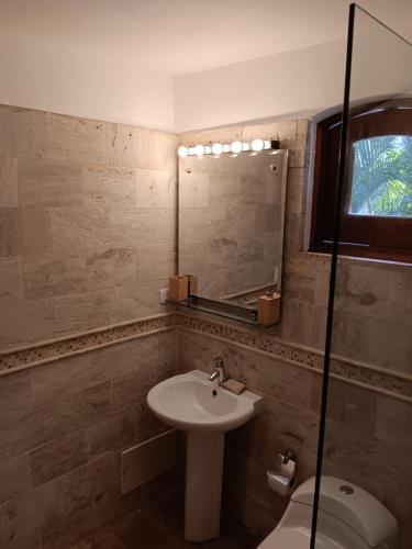 een badkamer met een wastafel, een toilet en een spiegel bij Newly Renovated Seaside Oasis at Bonita Village in Las Terrenas