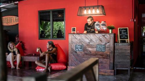 un hombre y dos mujeres sentados en un bar en House of Lion Hostel en Pantai Cenang