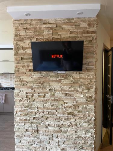 TV de pantalla plana en una pared de piedra en Квартира в центрі Світлі мрії Avenue Myru35 en Chernihiv