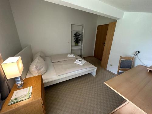 a room with a bed and a table and a lamp at Landhotel Maiergschwendt inkl Chiemgaukarte in Ruhpolding
