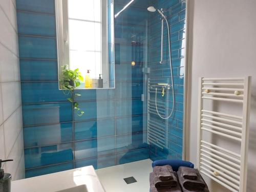 La salle de bains est pourvue de murs carrelés bleus et d'une douche. dans l'établissement Spacieux T2 rénové à neuf - Hyper centre de Blois, à Blois