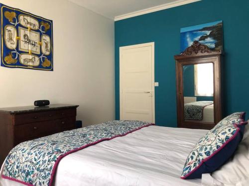 - une chambre avec des murs bleus, un lit et un miroir dans l'établissement Spacieux T2 rénové à neuf - Hyper centre de Blois, à Blois