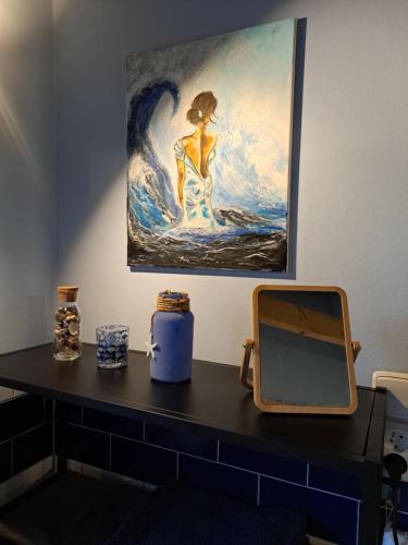 a desk with a mirror and a painting on the wall at Útulný apartmán in Bohatice