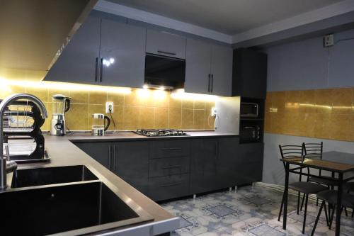 a kitchen with black cabinets and a sink and a table at Sweet Sleep hostel in Yerevan