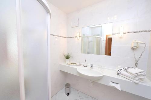 a white bathroom with a sink and a mirror at City-Hotel Mödling in Mödling