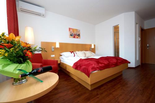 Habitación de hotel con cama y sofá rojo en City-Hotel Mödling, en Mödling