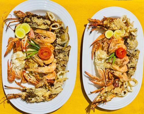 two plates of food with shrimp and pasta on a table at The Kingslayer Resort in Negombo