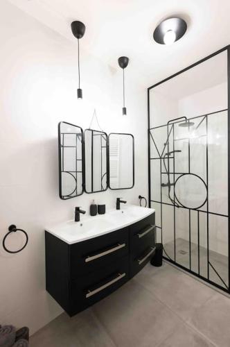 une salle de bain avec un lavabo et deux miroirs dans l'établissement Appartement T3 la perle verte, à Agde