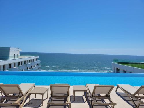 a pool with chairs and the ocean in the background at TGM Sunrise View in Infinity Pool & Spa Resort in Mamaia Sat/Năvodari