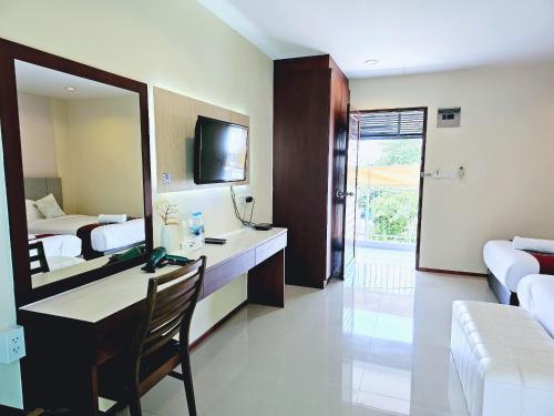 a hotel room with a desk and a mirror at STAYHERE@AIRPORT SERVICE APARTMENT in Ban Bo Han