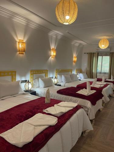 a hotel room with three beds with red and white sheets at Hôtel Bia Besta in Boumalne