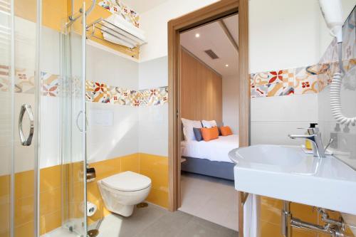 a bathroom with a toilet and a sink and a bed at Hotel O Sole Mio in SantʼAgata sui Due Golfi