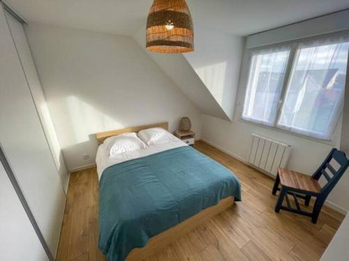 ein Schlafzimmer mit einem Bett und einem Stuhl auf einem Dachboden in der Unterkunft Ty Glas charmante maison 200 m de la plage in Ploudalmézeau