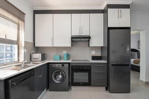 a kitchen with white cabinets and a dishwasher at Ballito Village Luxury Apartments in Ballito