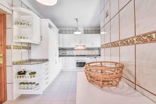 una cocina con armarios blancos y una cesta de mimbre en Villa Angeles Tur, en Calpe