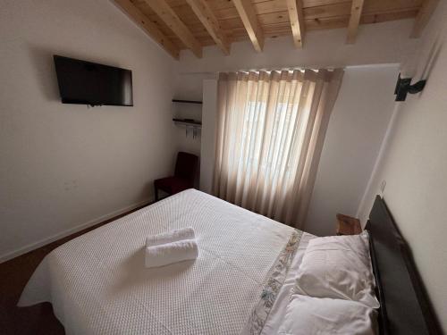 a bedroom with a white bed and a television at Casa da Pipela 