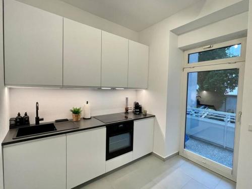 a white kitchen with white cabinets and a window at Stylisches Apartment in zentraler Lage mit Balkon in Karlsruhe